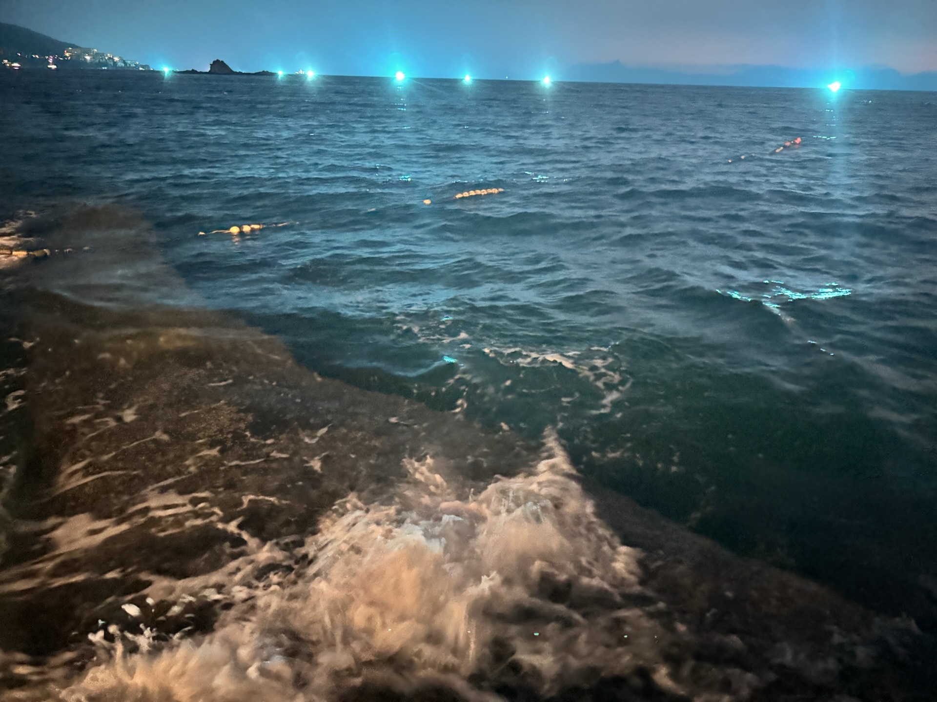 浪花打在岩石上，岩面被蓝色灯光染亮